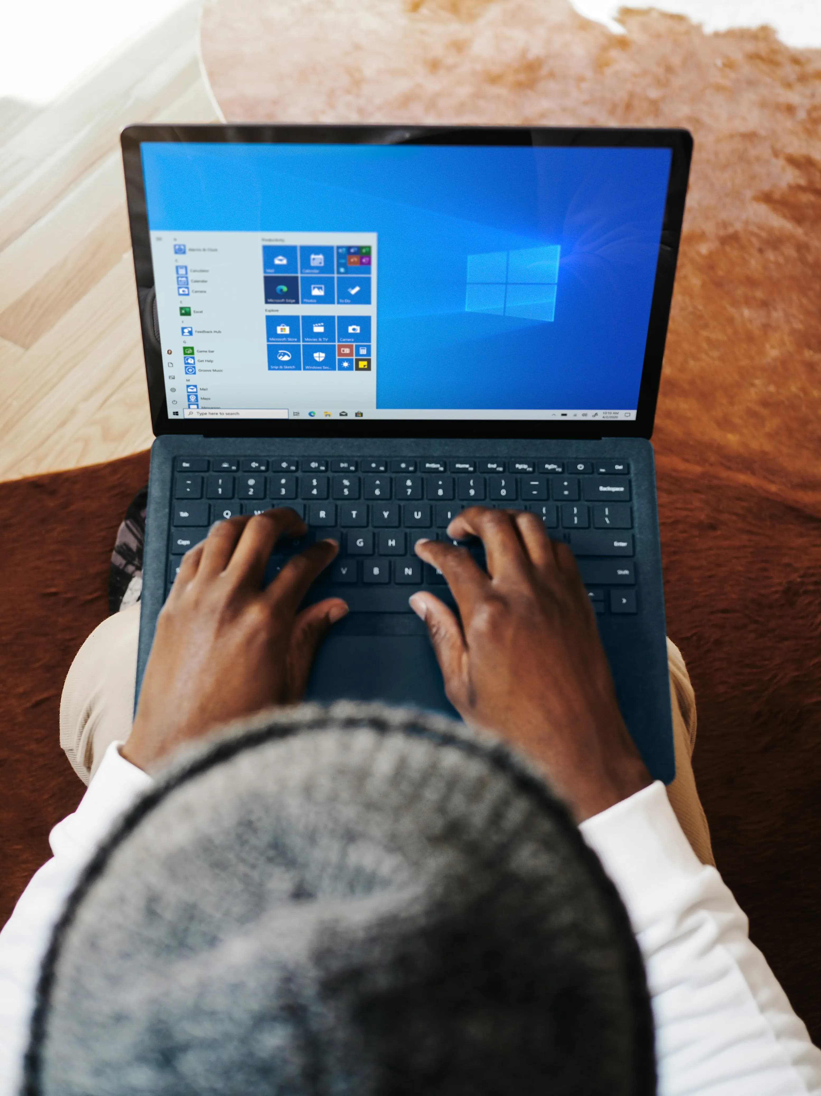 Bovenaanzicht van iemand die werkt op een Microsoft Surface laptop met het Windows startmenu open