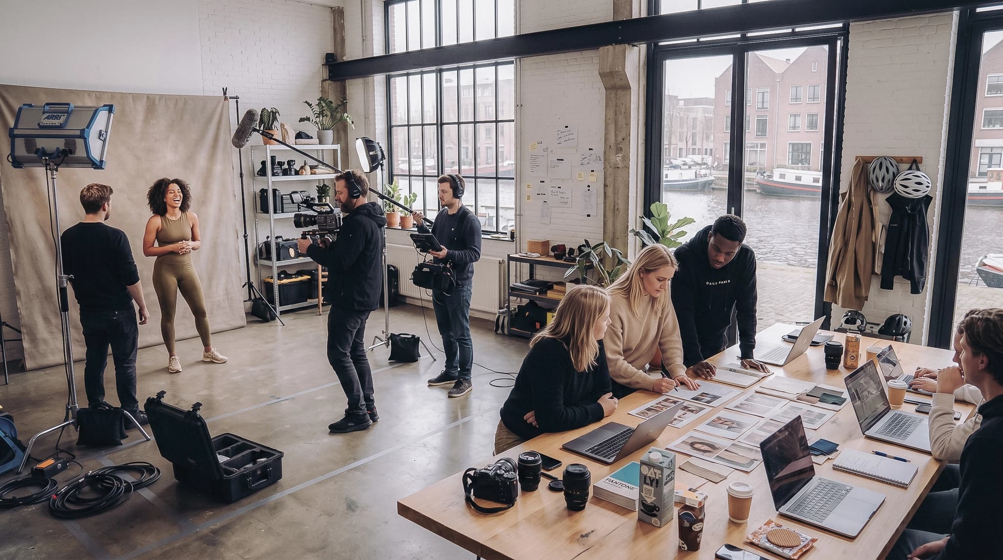 Creatief team aan het werk in een Nederlandse studio met videoshoot op de achtergrond en laptops op de werktafel.