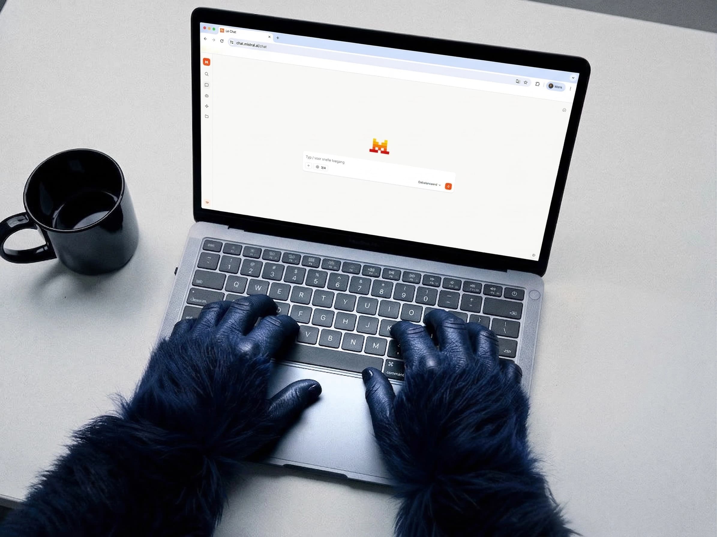 Blauwe gorilla handen typen op een laptop met de Mistral interface open op het scherm, naast een kop koffie